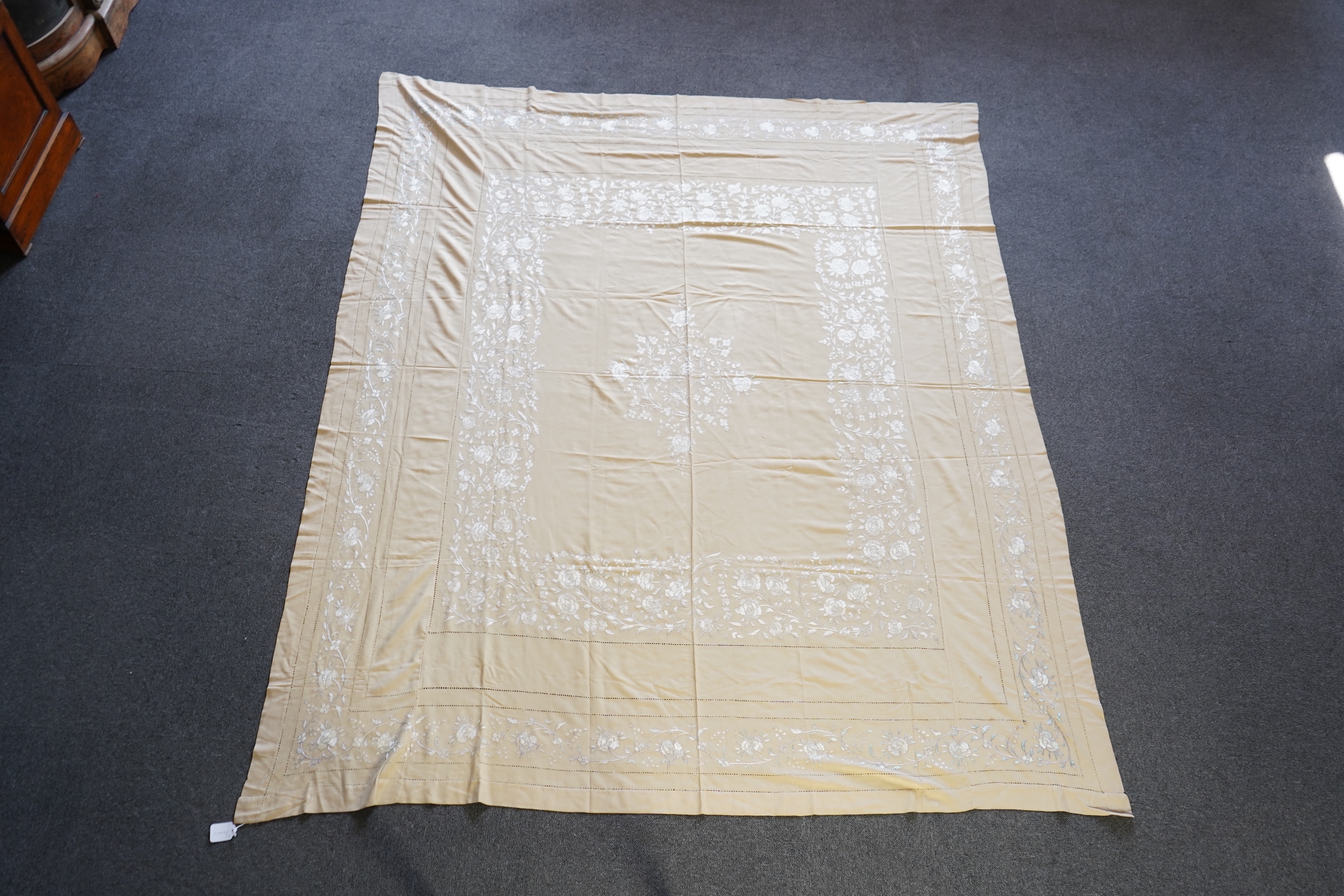 A 1920’s heavy shantung silk hand embroidered table cover. Worked with decorative rows of button hole stitch. Embroidered with white, green and blue silk flowers. 240cm x 204cm. Condition - some fine holes near corners,